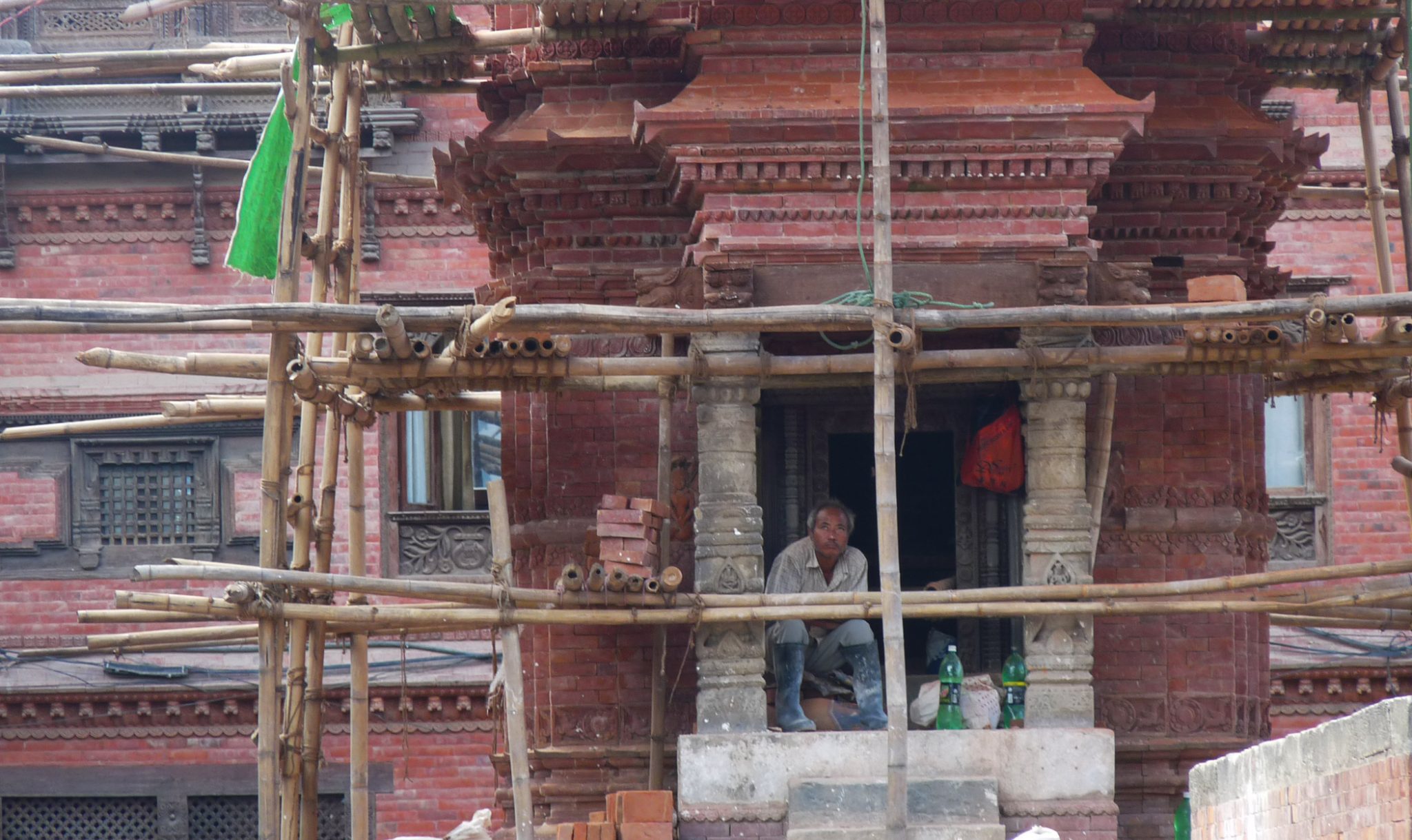A man sits in the damaged entrance to a temple.